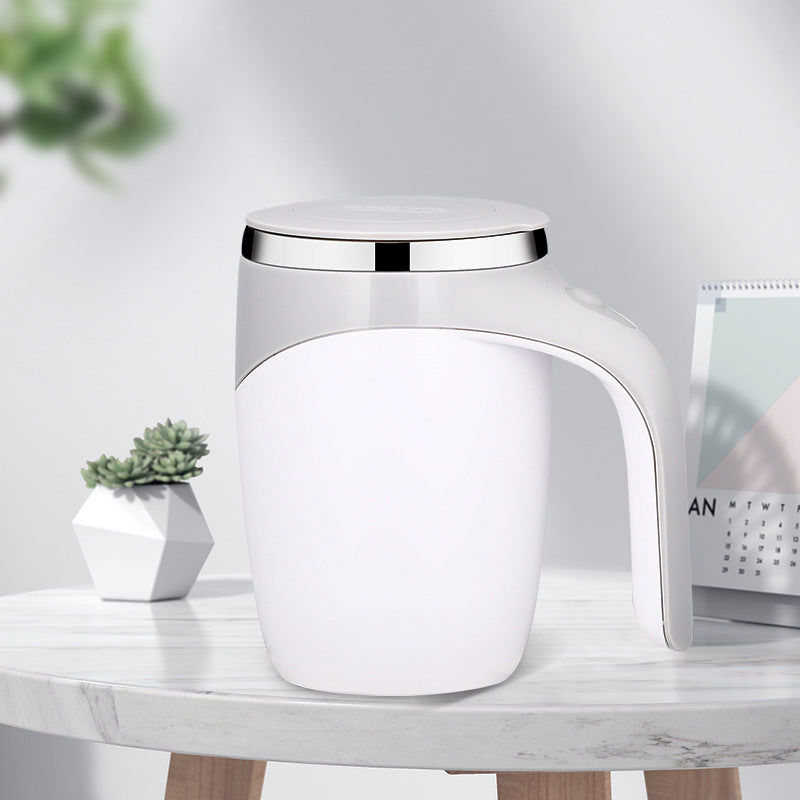White auto stirring mug on a shelf beside a small green plant